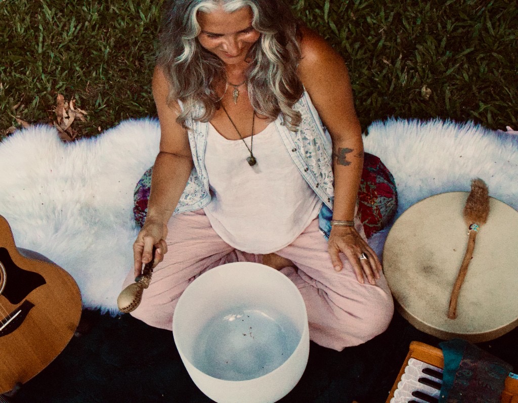 Amanda playing a crystal singing bowl during a sound healing session outdoors
