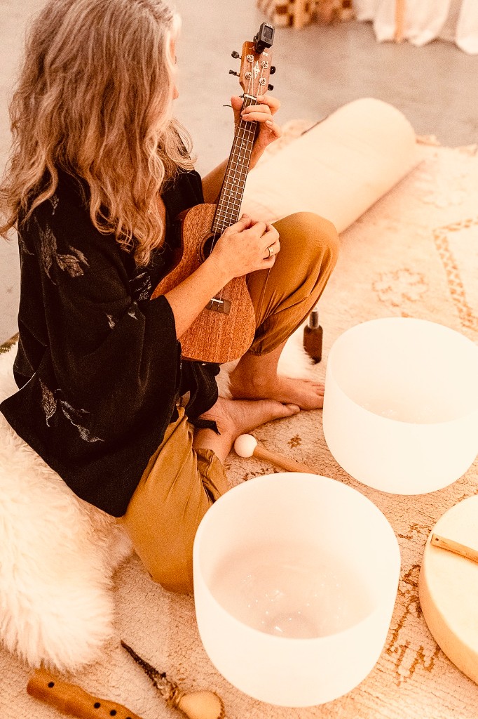 Amanda playing ukulele surrounded by crystal singing bowls and sacred instruments