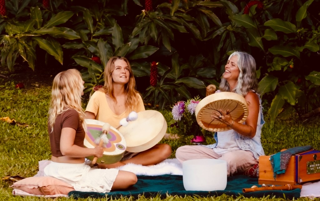Sound Play group gathering with frame drums and a crystal singing bowl in a garden setting